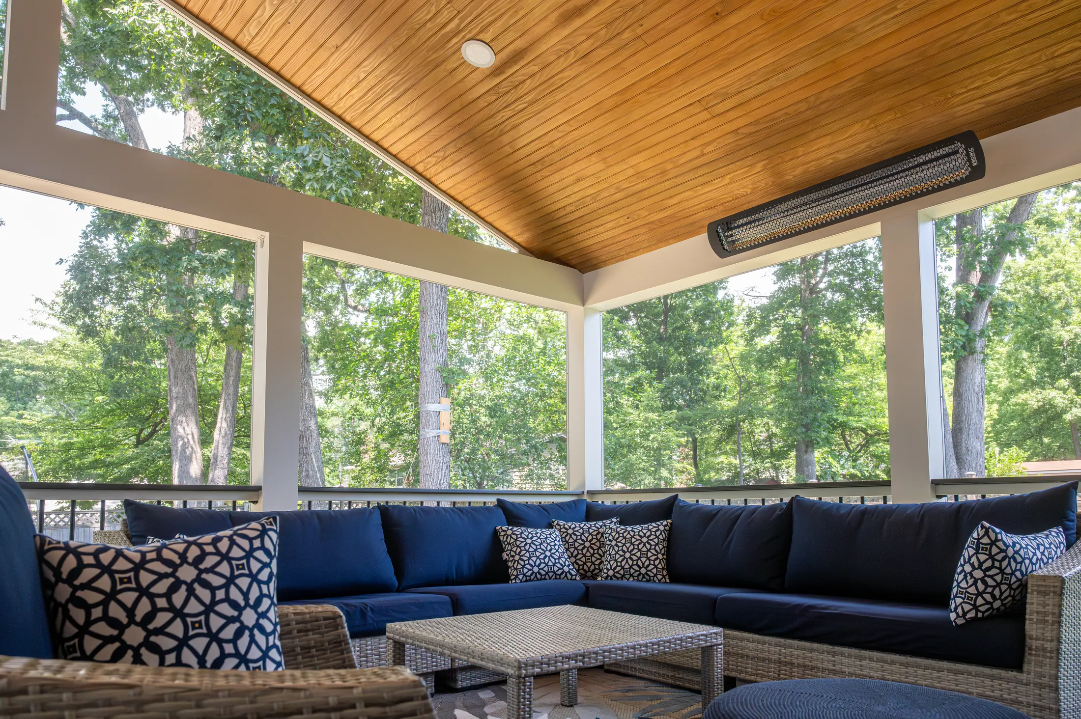 Screened porch with a cedar plank ceiling, heaters and a navy sectional