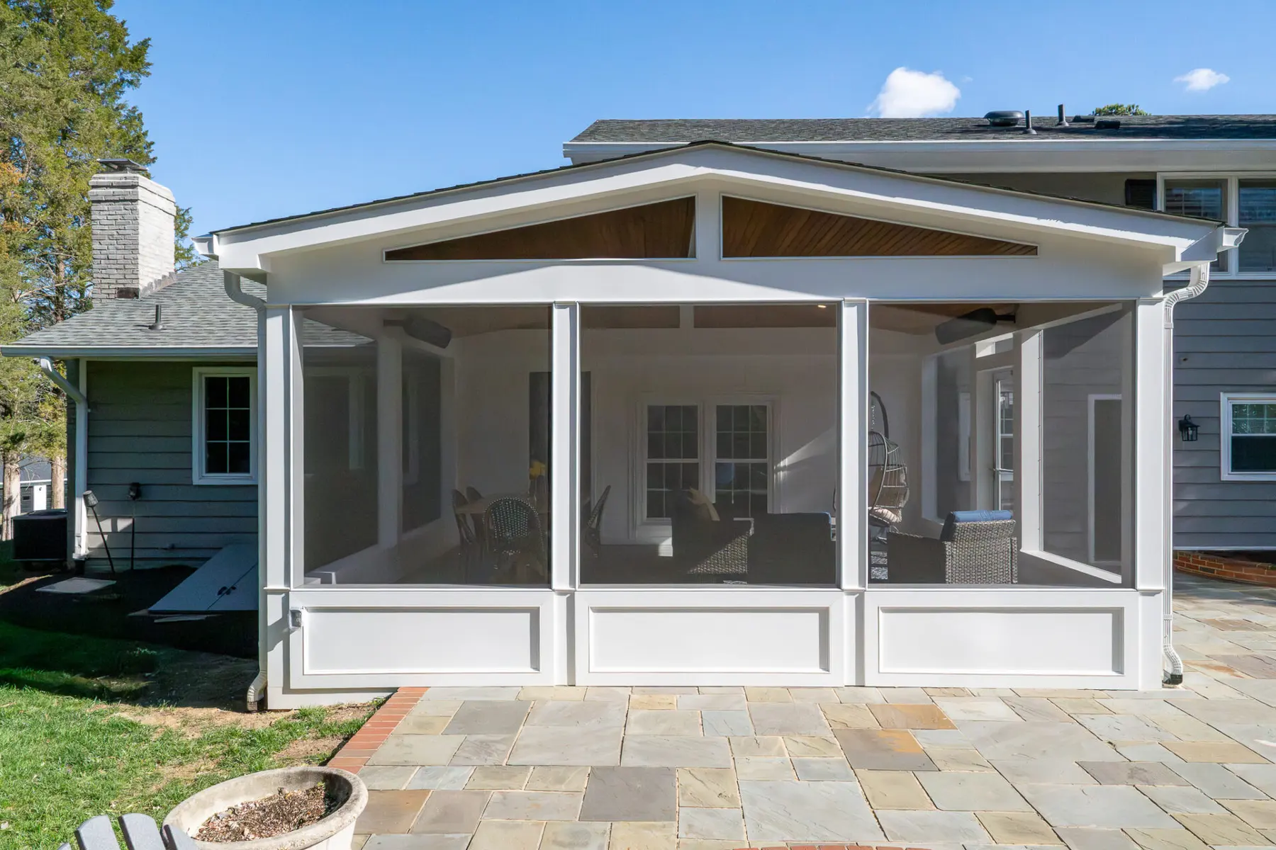 White gabled screened porch above a flagstone patio